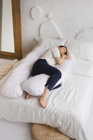 U-shaped maternity pillow with organic milk white cover displayed on a bed. By Minicamp